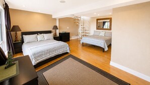 Ein modernes Schlafzimmer mit einem großen Bett, einem Nachttisch, einer Lampe, einer Kommode, einer Wendeltreppe und einem Spiegel an der Wand.