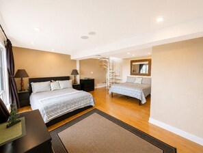 A modern bedroom with a large bed, a nightstand, a lamp, a dresser, a spiral staircase, and a mirror on the wall. - Secluded Romantic Getaway Overlooking Shasta Lake (Lakehead)