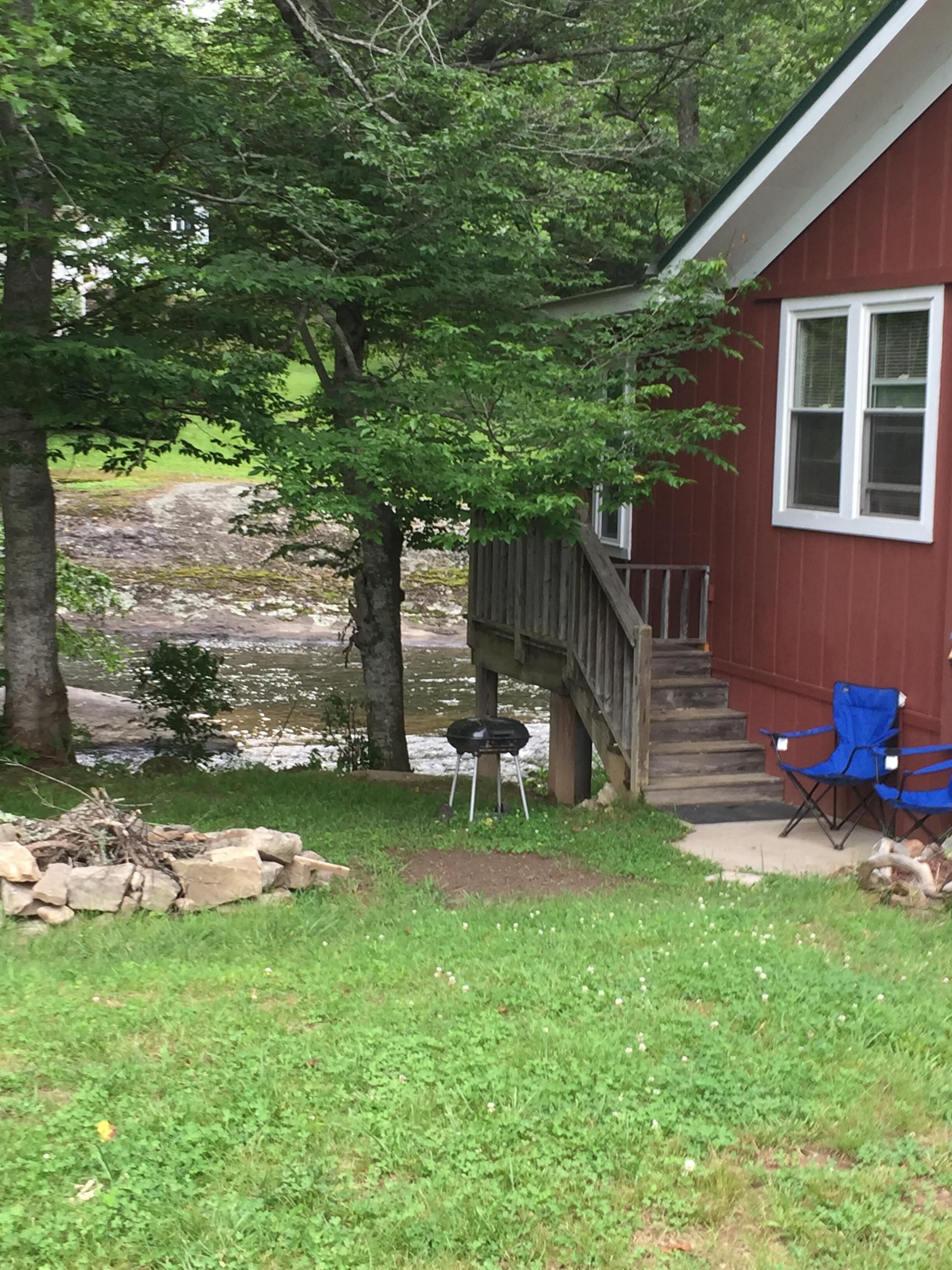 A red house with a deck, a small outdoor grill, and a blue chair.