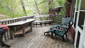 A wooden deck with a table and chairs, overlooking a forested area. - River's Edge Cabin - Swim - Kayak - Fish From Your Backyard !!!! (Franklin)