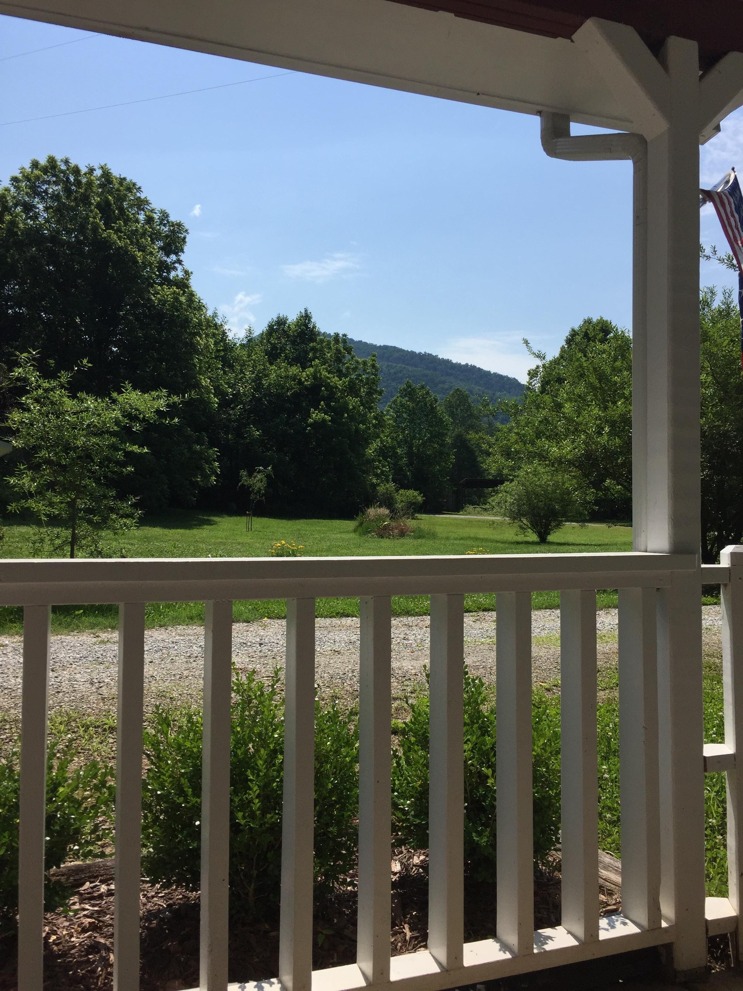 A porch with a view of a grassy field and trees.