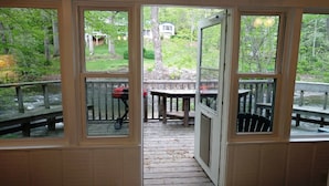 A wooden deck with a table and chairs, a grill, and a view of a house and trees. - River's Edge Cabin - Swim - Kayak - Fish From Your Backyard !!!! (Franklin)