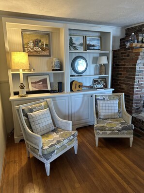 Relax in this inviting living room with a classic design, featuring a brick fireplace, upholstered chairs, and a console table.