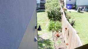 A wooden staircase leading to a backyard with a fence, a garden, and a bicycle. - Top loft garage suite close to Whyte Ave & University. Quick access to Downtown. (Edmonton)