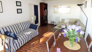 Una sala de estar con un sofá a rayas, una mesa de comedor con un florero y una silla blanca.