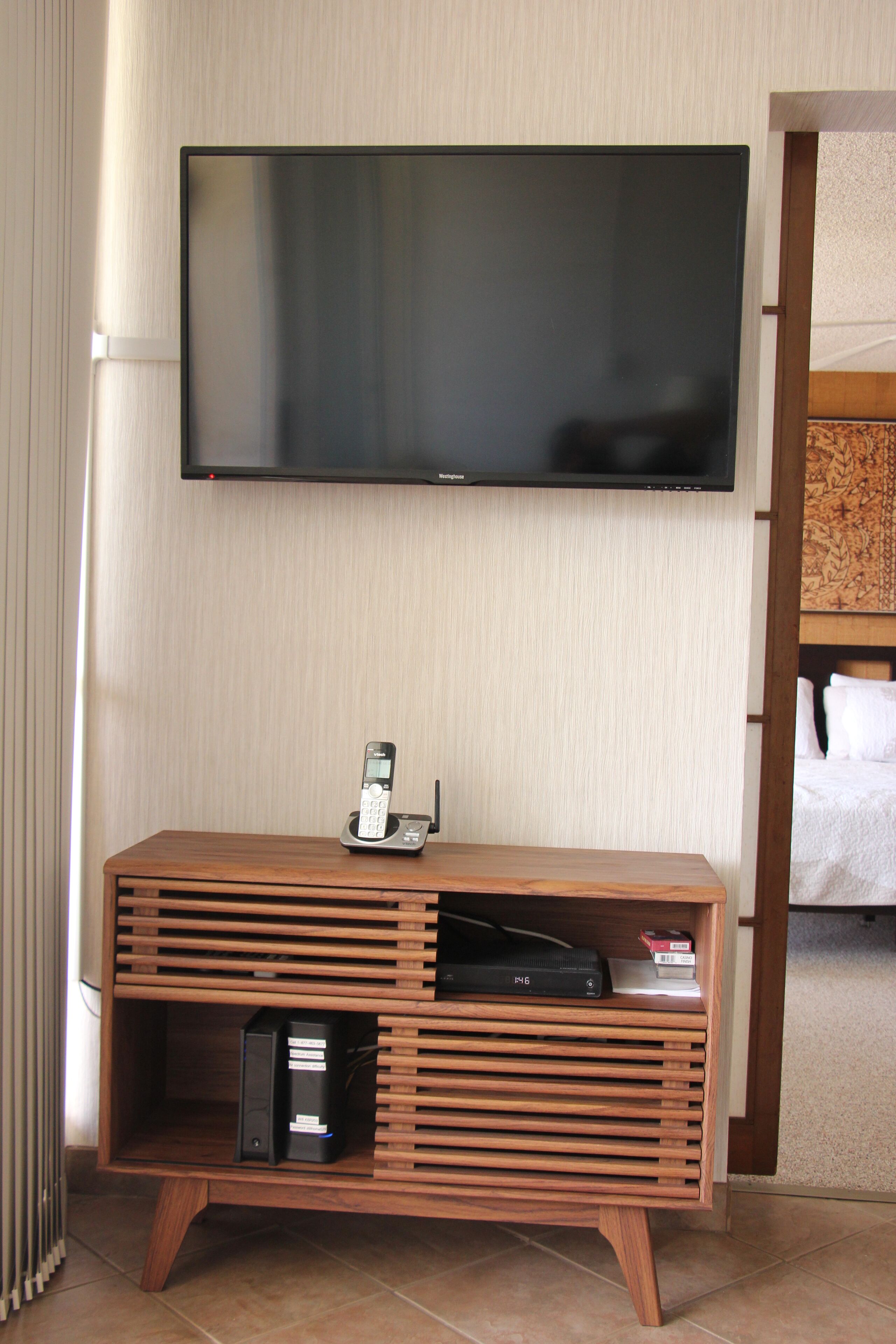 A wooden entertainment unit with a flat-screen TV, a telephone, and a DVD player.