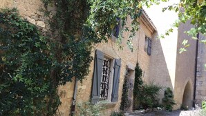 Un callejón estrecho flanqueado por edificios de piedra, uno de ellos con una ventana que muestra un letrero.