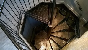 Una escalera de caracol con barandilla de metal y suelo texturizado.