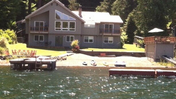 A two-story house with a dock extending into a lake, surrounded by dense forest. - Bobbi's Beach House is a spacious waterfront home with something for everyone! (Mount Vernon)