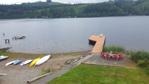 A lakeside dock with a small wooden structure, several kayaks, and red chairs near the water's edge. - Bobbi's Beach House is a spacious waterfront home with something for everyone! (Mount Vernon)