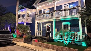 A two-story house with a porch decorated with lights and garlands, a garage, and a driveway.