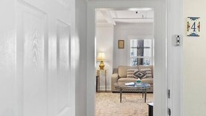 A hallway leading to a living room with a sofa, coffee table, and lamp.
