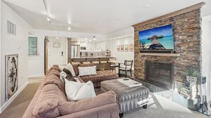 A modern living room with a fireplace, a sofa, and a dining area. - Highly Rated Silver King - Steps to Skiing - 2BD/2BA (Park City)