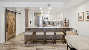 A modern kitchen with a central island, bar stools, and a dining table. - Highly Rated Silver King - Steps to Skiing - 2BD/2BA (Park City)