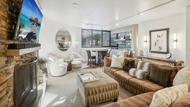 A modern living room with a fireplace, a dining area, and a kitchen visible through an open door. - Highly Rated Silver King - Steps to Skiing - 2BD/2BA (Park City)
