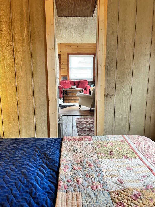 A cozy room with a bed, a red sofa, and a window with blinds.