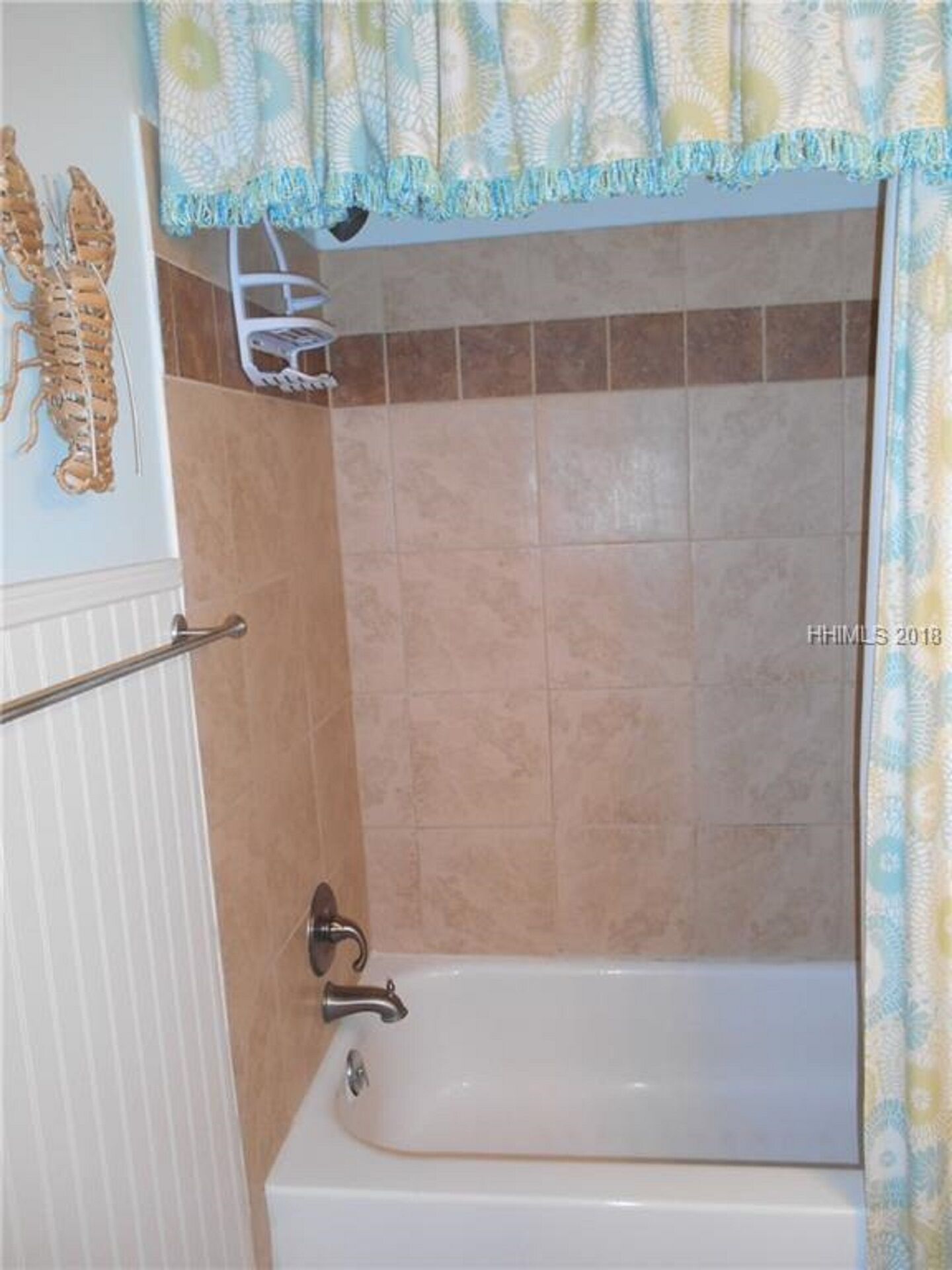 Um banheiro com banheira, porta-toalhas e um detalhe decorativo na parede.