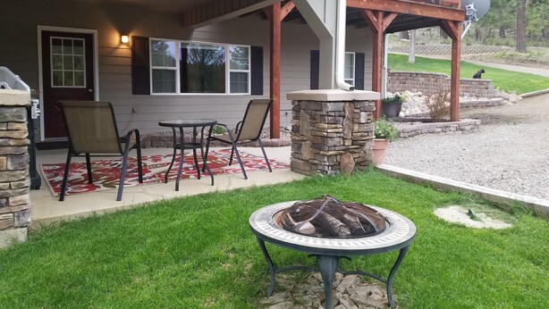A house with a covered porch, stone pillars, a fire pit, and a satellite dish. - SADDLE MOUNTAIN ESCAPE (Clancy)