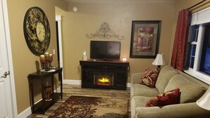 A living room with a fireplace, a sofa, a television, and a decorative wall clock. - SADDLE MOUNTAIN ESCAPE (Clancy)