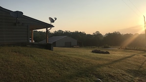 Casa rural con antena parabólica, garaje y jardín césped.