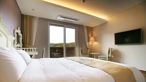 Habitación de hotel con una cama grande, un televisor en la pared y vistas al exterior a través de una puerta corrediza.