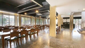 Un comedor espacioso con mesas y sillas largas, ventanas amplias y un moderno diseño de techo industrial.