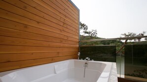 Un baño moderno con pared de madera, cabina de ducha de cristal y bañera blanca.