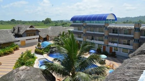A resort with a pool area, thatched-roof buildings, and a modern structure with a blue roof.