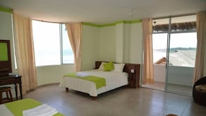 A hotel room with a bed, a desk, and a view of the beach.