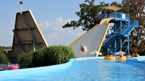 A water park with a large water slide, a pool, and a lifeguard tower. - Lake Breeze Resort  (Camdenton)