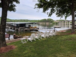 A lakeside dock area with white Adirondack chairs, a covered seating area, and a kayak. - Lake Breeze Resort  (Camdenton)