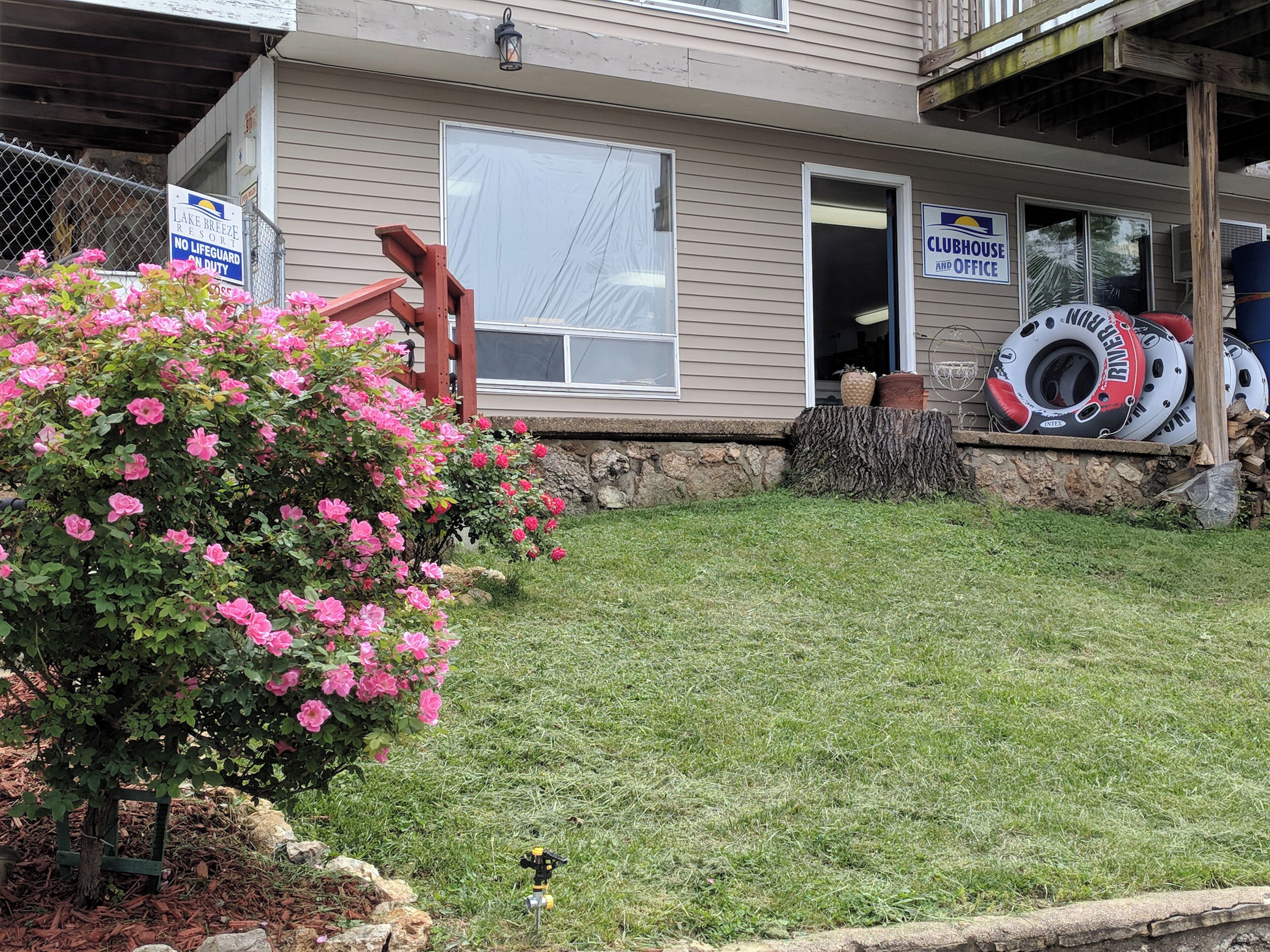 A house with a sign indicating no lifeguard on duty, a Clubhouse and Office sign, and a pile of inflatable rings.