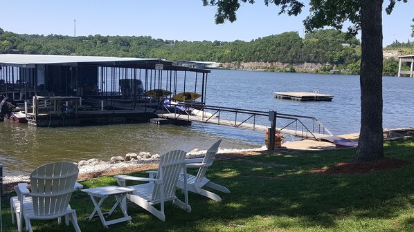 A lakeside dock with a covered seating area, a small boat, and a picnic table with chairs. - Lake Breeze Resort  (Camdenton)
