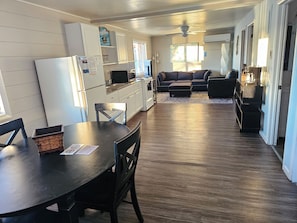 A compact kitchen with a refrigerator, microwave, and dining area with a table and chairs. - Lake Breeze Resort  (Camdenton)