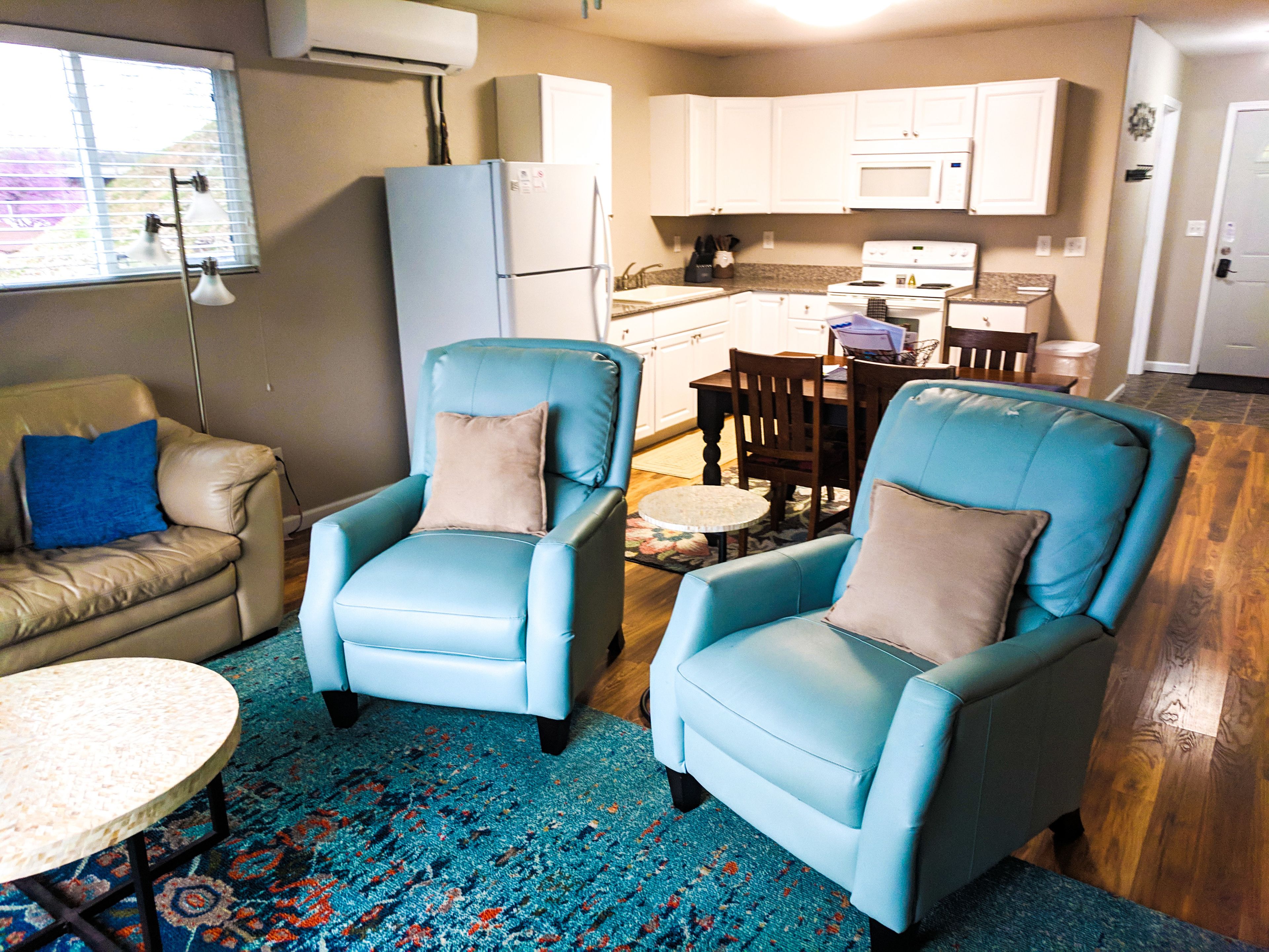 A living room with two blue armchairs, a beige sofa, and a small round table.