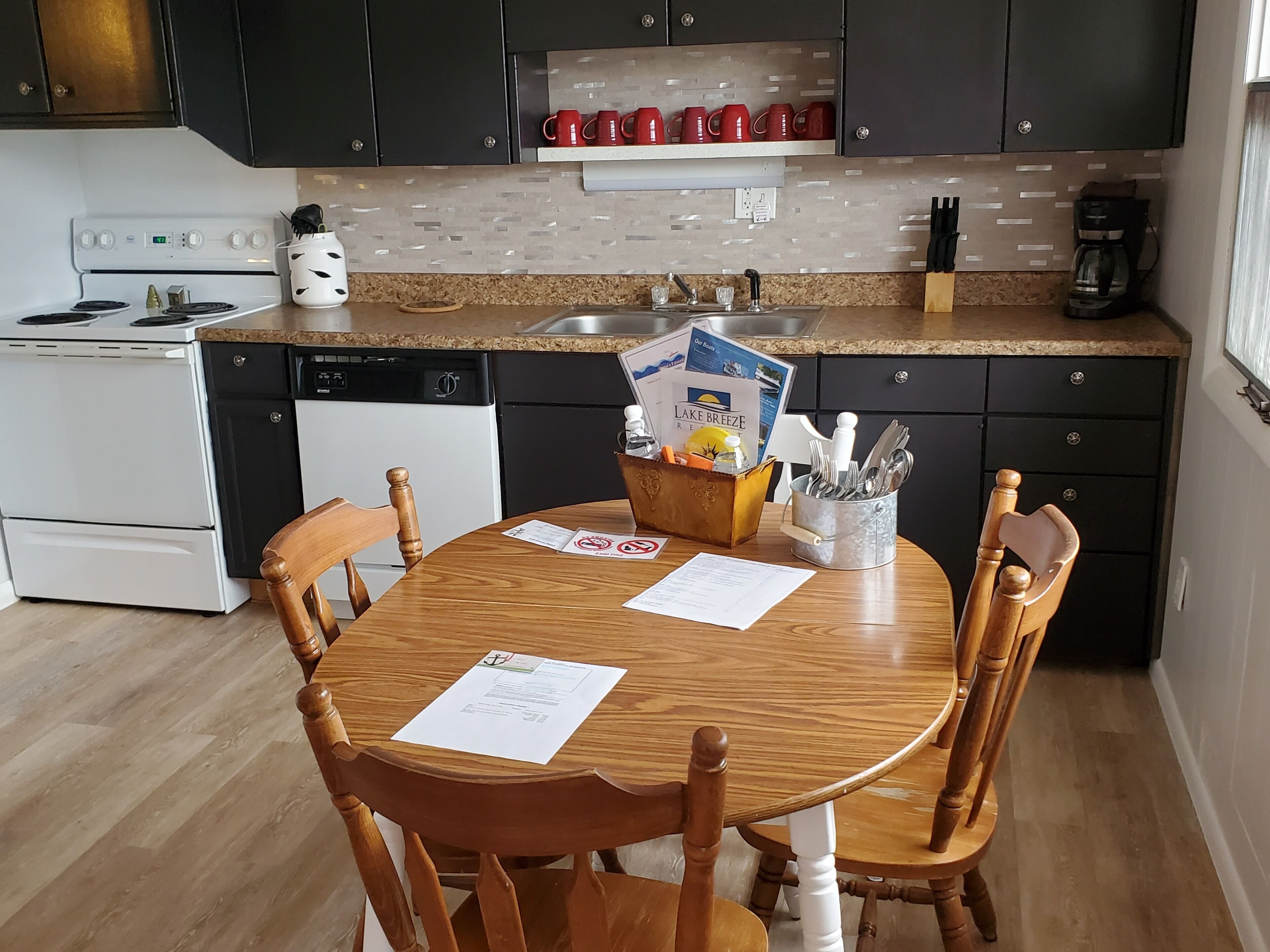 A kitchen with a dining table, chairs, a coffee maker, and a dishwasher.