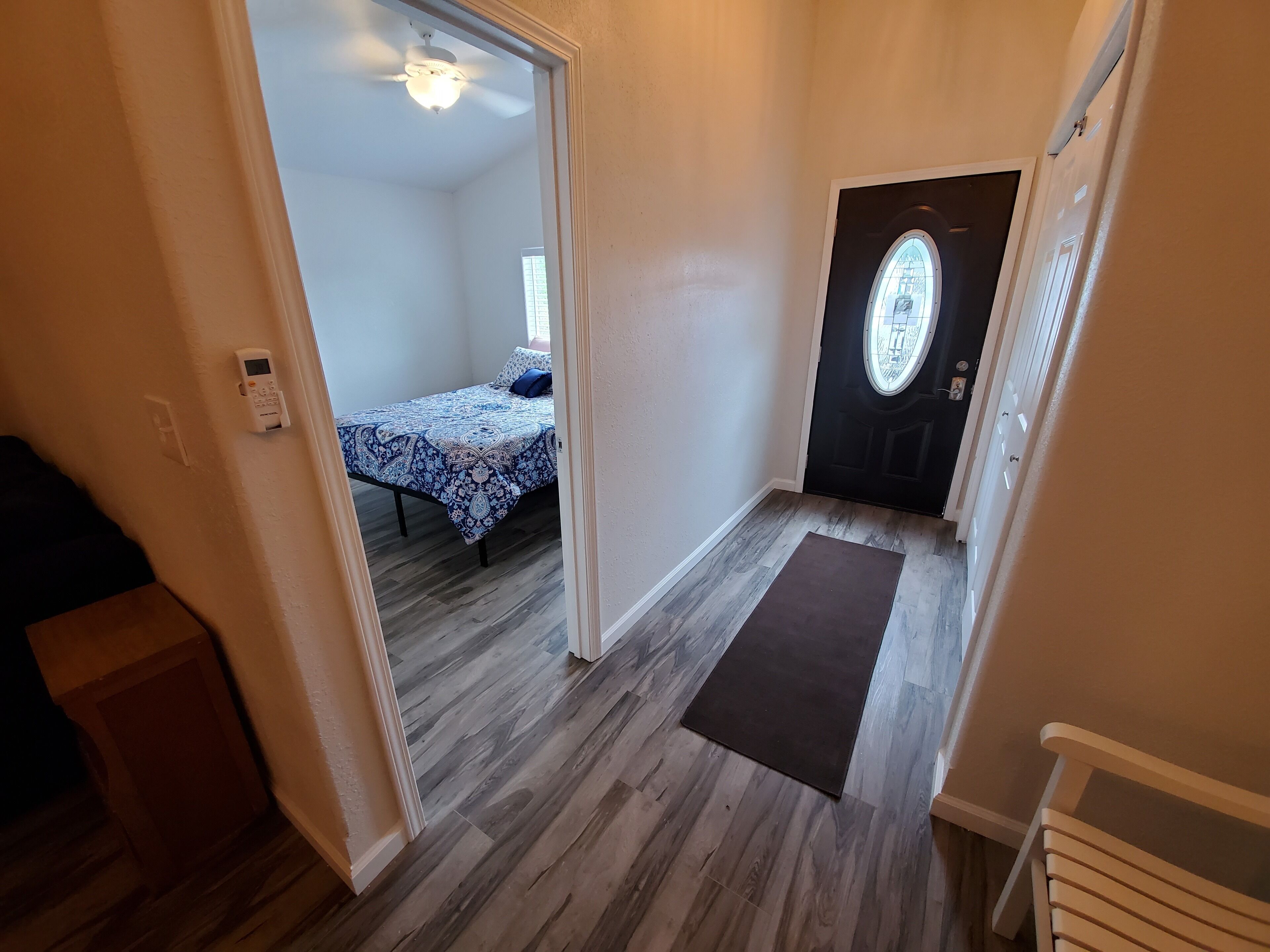 Un dormitorio con cama, una puerta con ventana y un ventilador de techo.