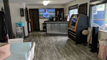 Una habitación con piso de madera, televisión, máquina expendedora y mostrador con cafetera.
