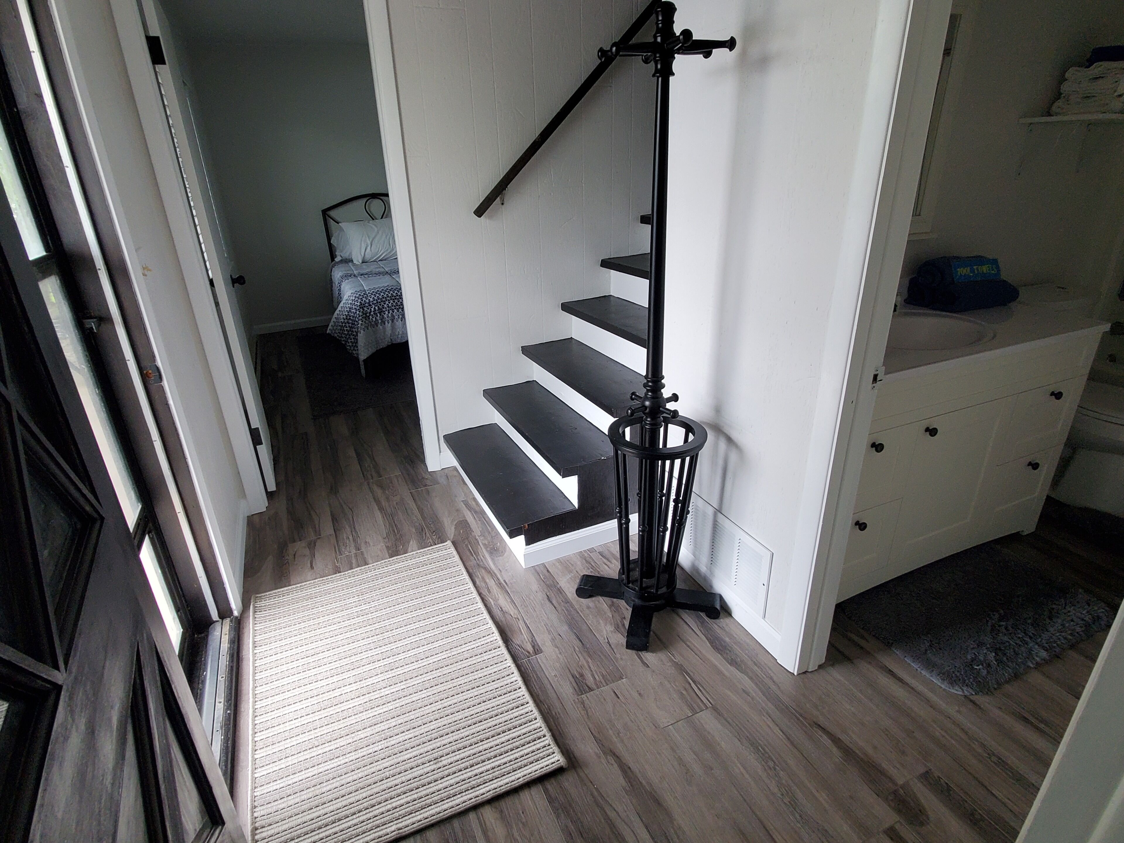 Una escalera con barandilla negra, pared blanca y piso de madera.