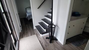Una escalera con barandilla negra, pared blanca y piso de madera.