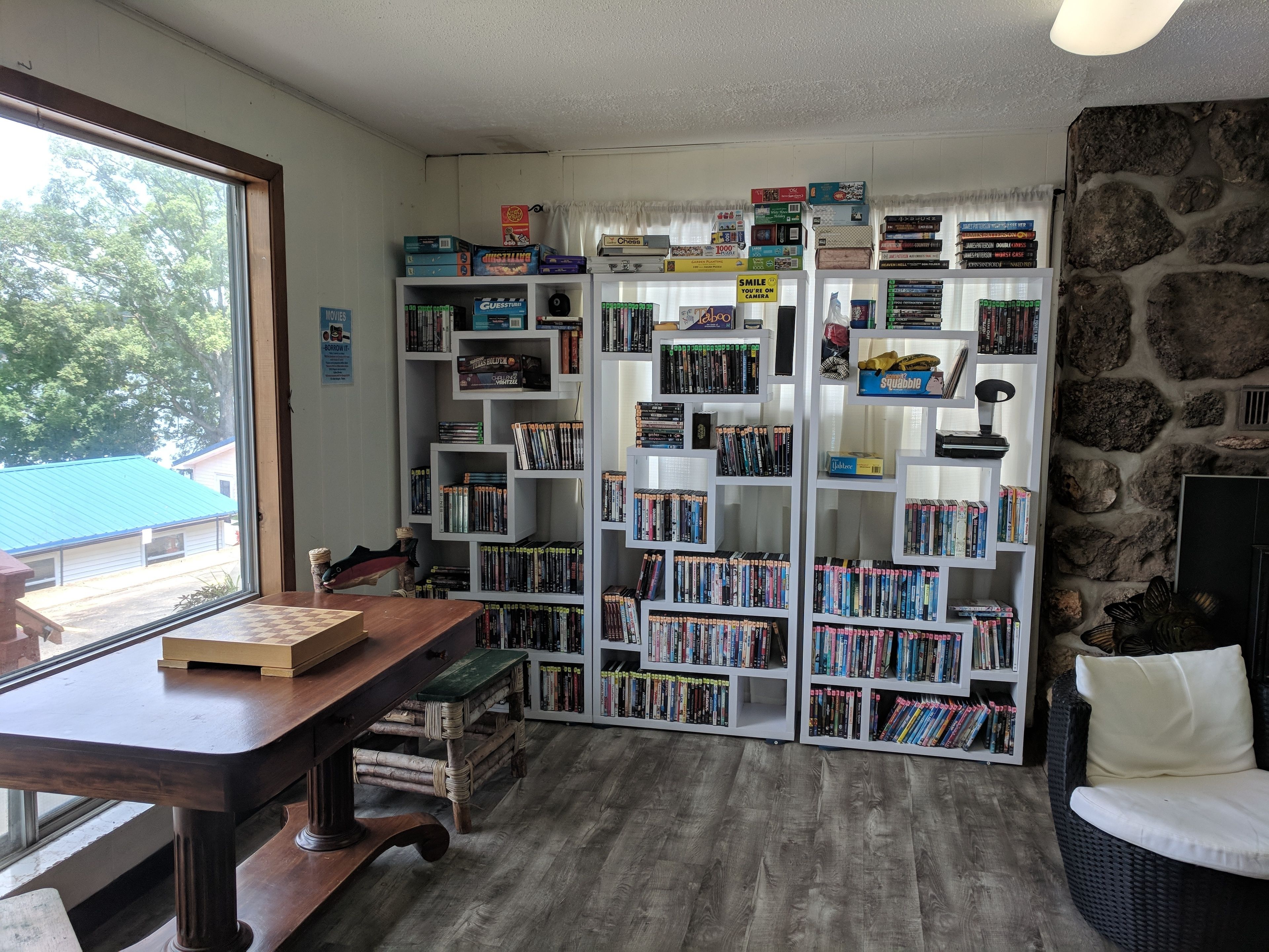 A cozy reading nook with a wooden desk, a stone wall, and a bookshelf filled with books and board games.