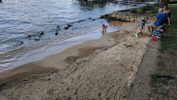 Vista del lago con una playa arenosa, un muelle y un muro de piedra.