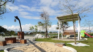 Un parque infantil con tobogán, estructura para escalar y zona de estar cubierta.