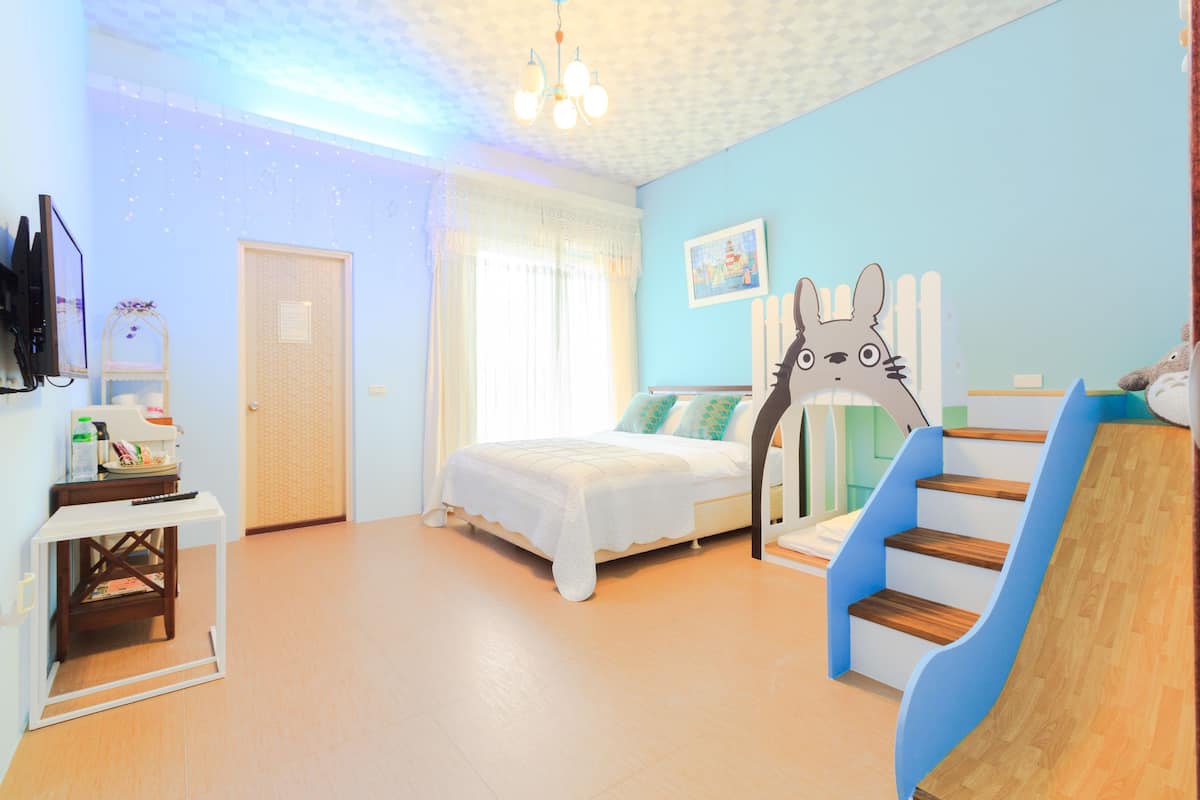 A bedroom with a bed, a desk, a chair, a window, and a staircase.