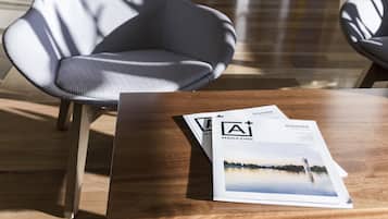 A wooden table with two magazines on it, a modern chair, and a wooden floor.