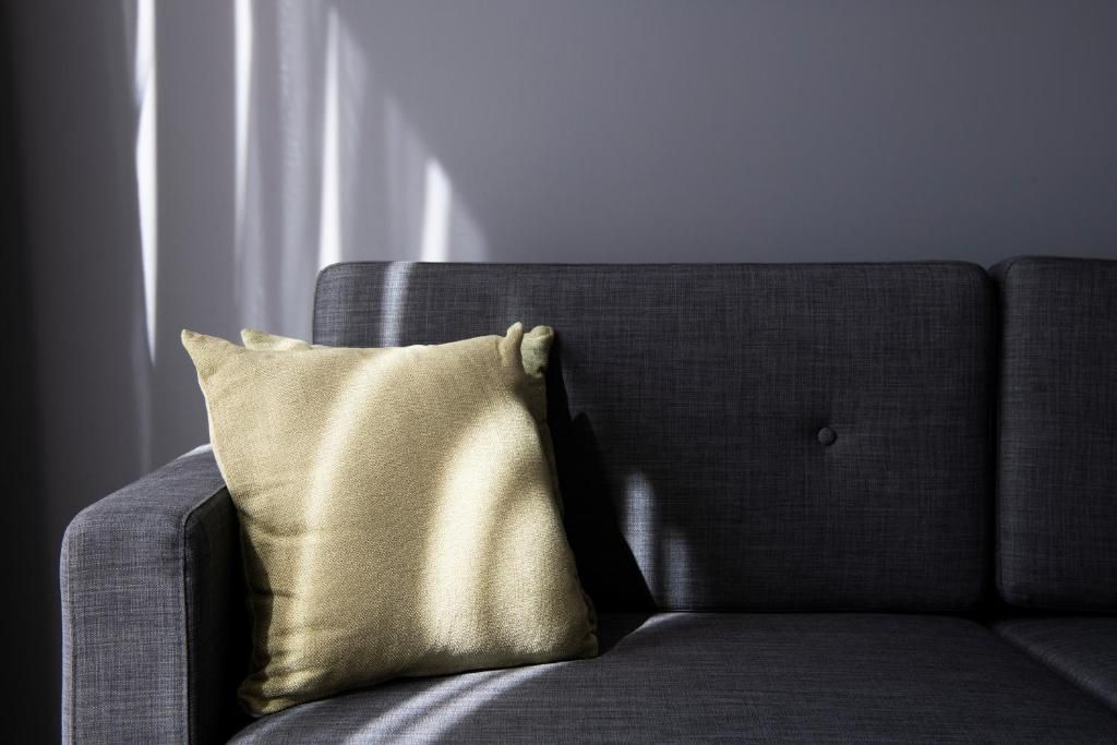 A grey sofa with a single cushion.