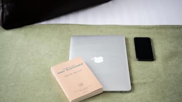 A laptop, a smartphone, and a notebook on a green fabric surface.