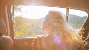 Una persona sentada junto a la ventana de un coche, con luz solar entrando.