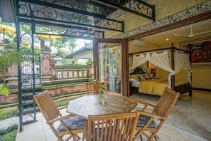 Une pièce avec un lit, une porte vitrée donnant sur l’extérieur et une table avec des chaises.