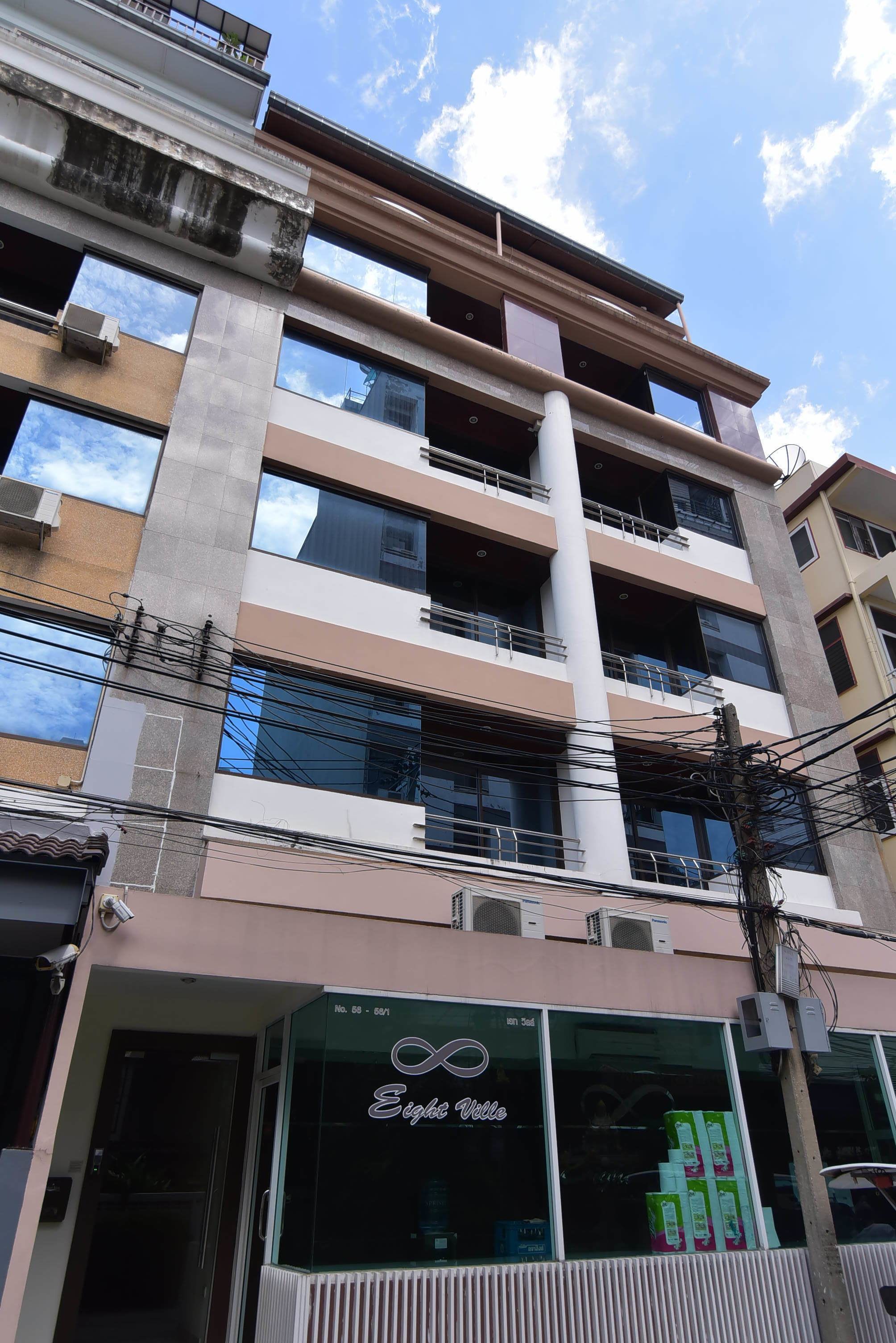 Un edificio de varios pisos con balcones, unidades de aire acondicionado y un escaparate con un letrero que dice "Eighteen Velle".